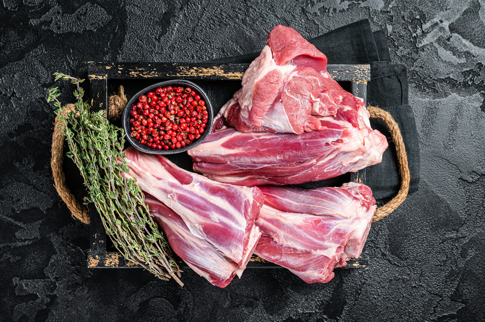 Fresh Raw lamb shanks with herbs and spices, mutton meat. Black background. Top view