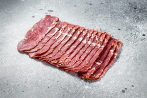 Turkish bacon Pastrami beef meat. Gray background. Top view